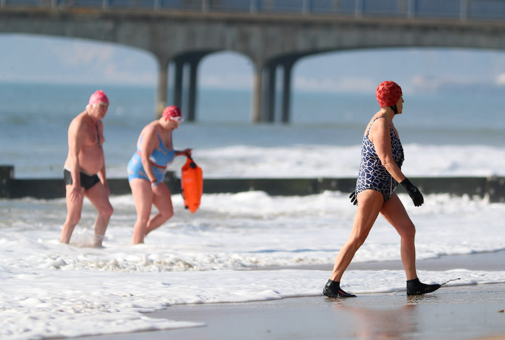 People leave the sea after an early morning swim as they enjoy the warm weather on Boscombe beach in Dorset (Picture: PA)