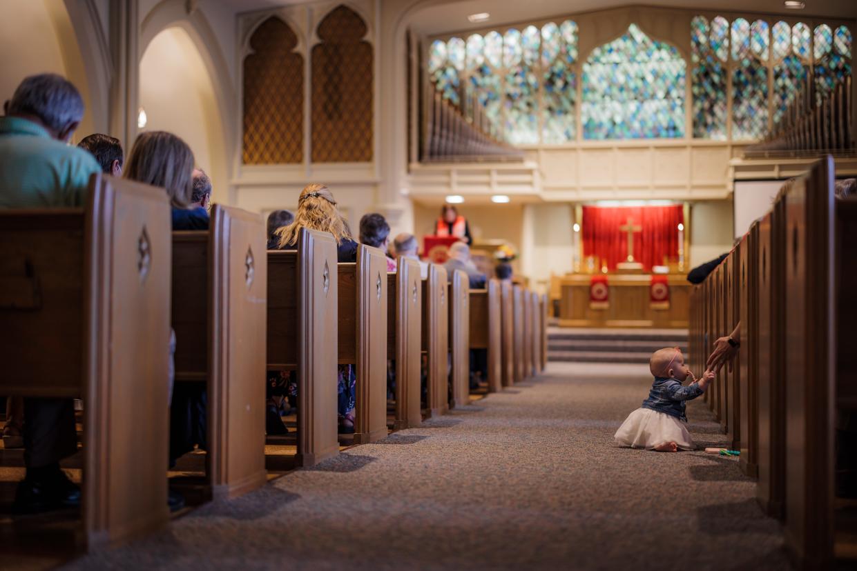 Collins Hubbard reaches for her mother's hand as she crawls down the aisle of First Christian Church during their last Sunday Service after serving the community for 125 years.