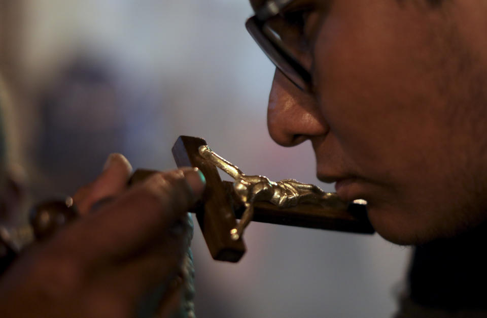 In this picture taken Monday, Jan. 6, 2020, spiritual indigenous guide Mariano Condori Flores holds a cross for parishioner Ruben Huanca to kiss outside San Francisco Church during the Three Kings Day celebrations in La Paz, Bolivia. Condori Flores was among several spiritual guides who performed traditional indigenous blessings outside the church on baby Jesus dolls after parishioners left the church. (AP Photo/Natacha Pisarenko)