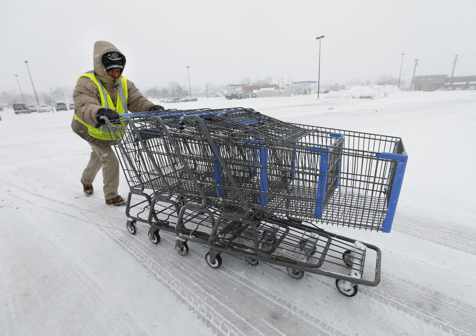 Anthony Avery pushes grocery carts during a snow storm in Roseville, Mich., Wednesday, March 12, 2014. The storm will likely move the Detroit area close to the seasonal snow total of 93.6 inches set in 1880-1881, according to the National Weather Service. (AP Photo/Paul Sancya)