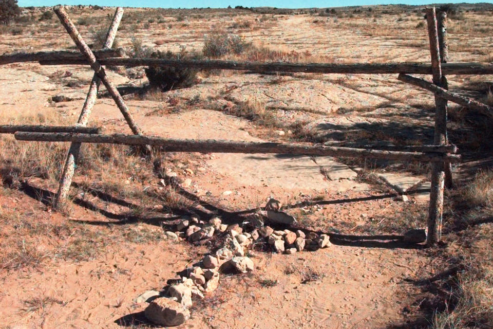 FILE - A cross made of stones rests below the fence in Laramie, Wyo., on Oct. 9, 1999, where a year earlier, University of Wyoming student Matthew Shepard was tied and pistol whipped into a coma. He later died. The murder of Shepard was a watershed moment for gay rights and LGBTQ+ acceptance in the U.S. (AP Photo/Ed Andrieski, File)