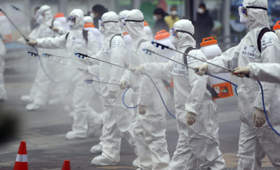 Army soldiers wearing protective suits spray disinfectant to prevent the spread of the new coronavirus at the Dongdaegu train station in Daegu, South Korea, Saturday, Feb. 29, 2020. (Kim Hyun-tai/Yonhap via AP)