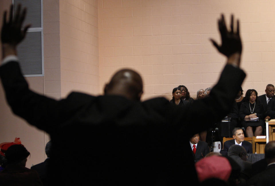 FILE - In this Sunday, Jan. 17, 2010 file photo, Richard Flegler, left, raises his arms during a church service attended by President Barack Obama, right, at the Vermont Avenue Baptist Church in Washington. On his first Martin Luther King Jr. holiday as president, Obama spoke at the church where King himself once spoke. He reflected on difficulties faced in pushing his agenda through Congress and the periodic distractions stemming from remarks about his race. (AP Photo/Pablo Martinez Monsivais)