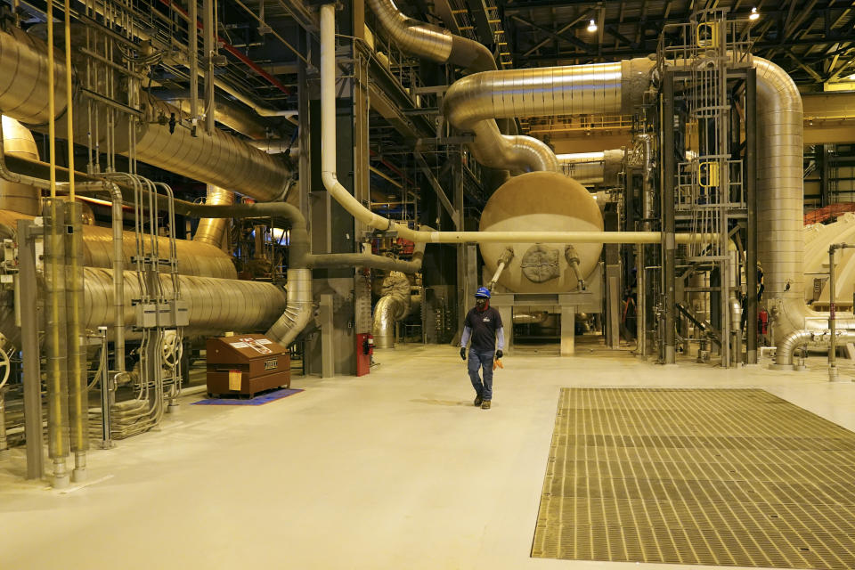 A worker walks past steam pipes at Georgia Power’s Plant Vogtle nuclear power plant.