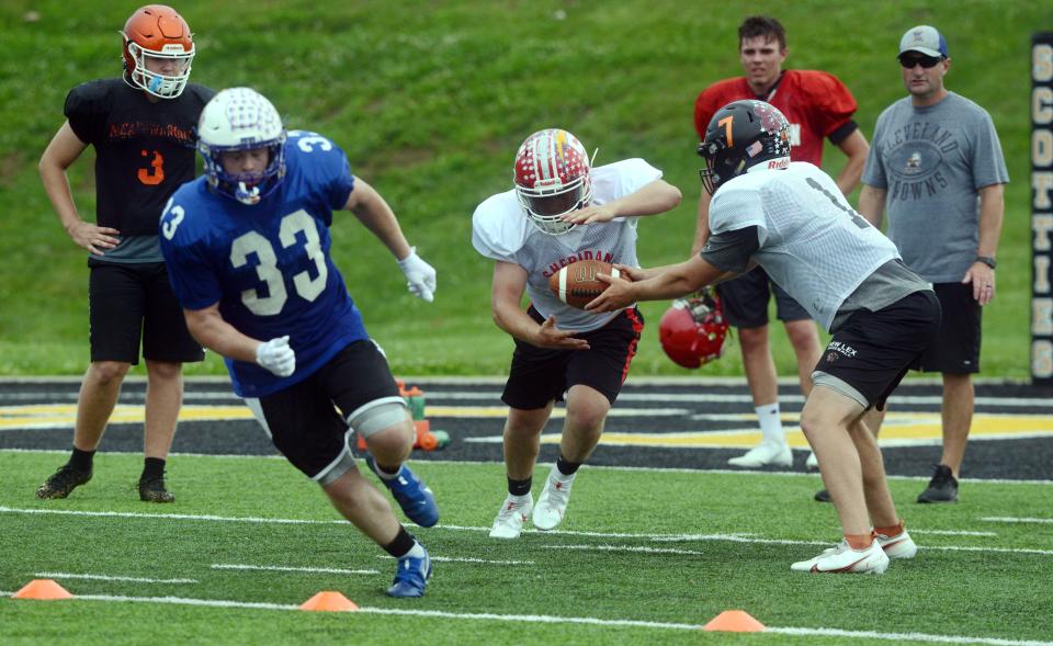 With Zanesville's Trey Whiteman leading the way, Sheridan's Jason Munyan takes a handoff from New Lexington's Hunter Kellogg during Muskingum Valley League All-Star practice on Monday at Tri-Valley's Jack Anderson Stadium in Dresden.