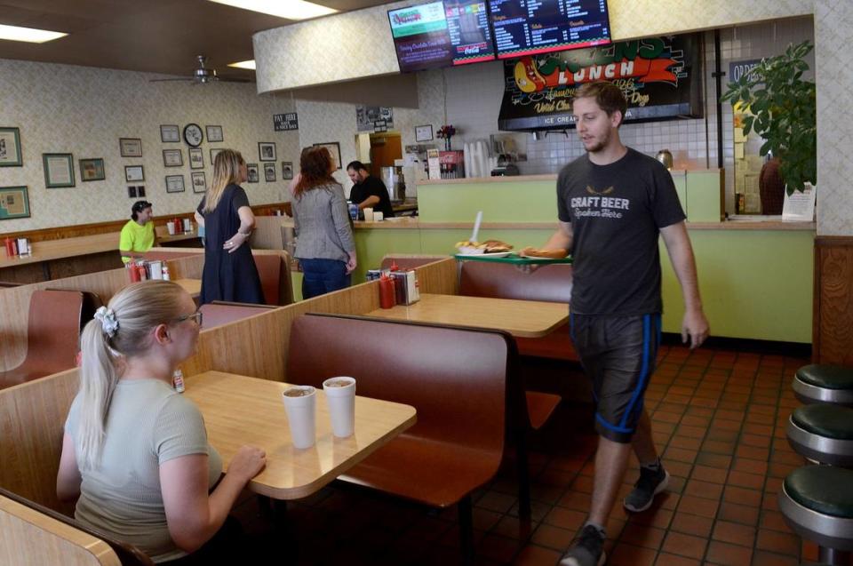 Casey Martin, right, 25, delivers lunch to Ashley Rodgers, 24, that the couple just ordered at Green’s Lunch in Charlotte, NC., on Thursday, Aug. 11, 2022. The Restaurant is nearly 100-year old business that is struggling with labor shortages and higher prices on everything from ingredients to cutlery.