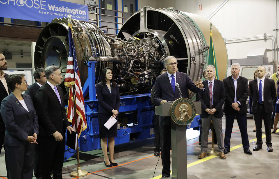 FILE - In this June 6, 2018 file photo, Washington Gov. Jay Inslee, center, speaks in front of an airplane engine at South Seattle College in Seattle. Washington state lawmakers announced Wednesday, Feb. 19, 2020 that they will introduce bills, at Boeing Co.'s request, to suspend the company's preferential business and occupation tax rate until there's a final determination from World Trade Organization regarding a long-running trade dispute. (AP Photo/Ted S. Warren, File)