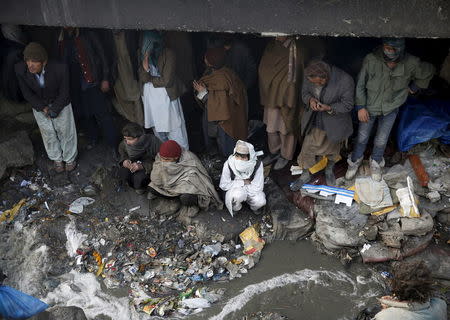 People shelter under the Pul-e Sokhta bridge in western Kabul, during a police round up of suspected drug addicts December 27, 2015. REUTERS/Ahmad Masood