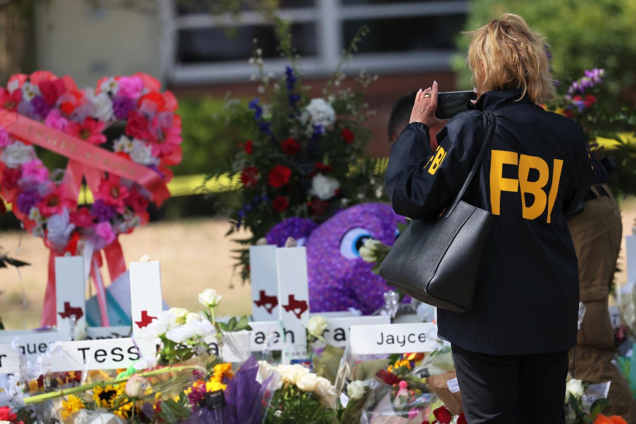 An FBI agent takes a photo of a memorial for victims of Tuesday's mass shooting at Robb Elementary School. 