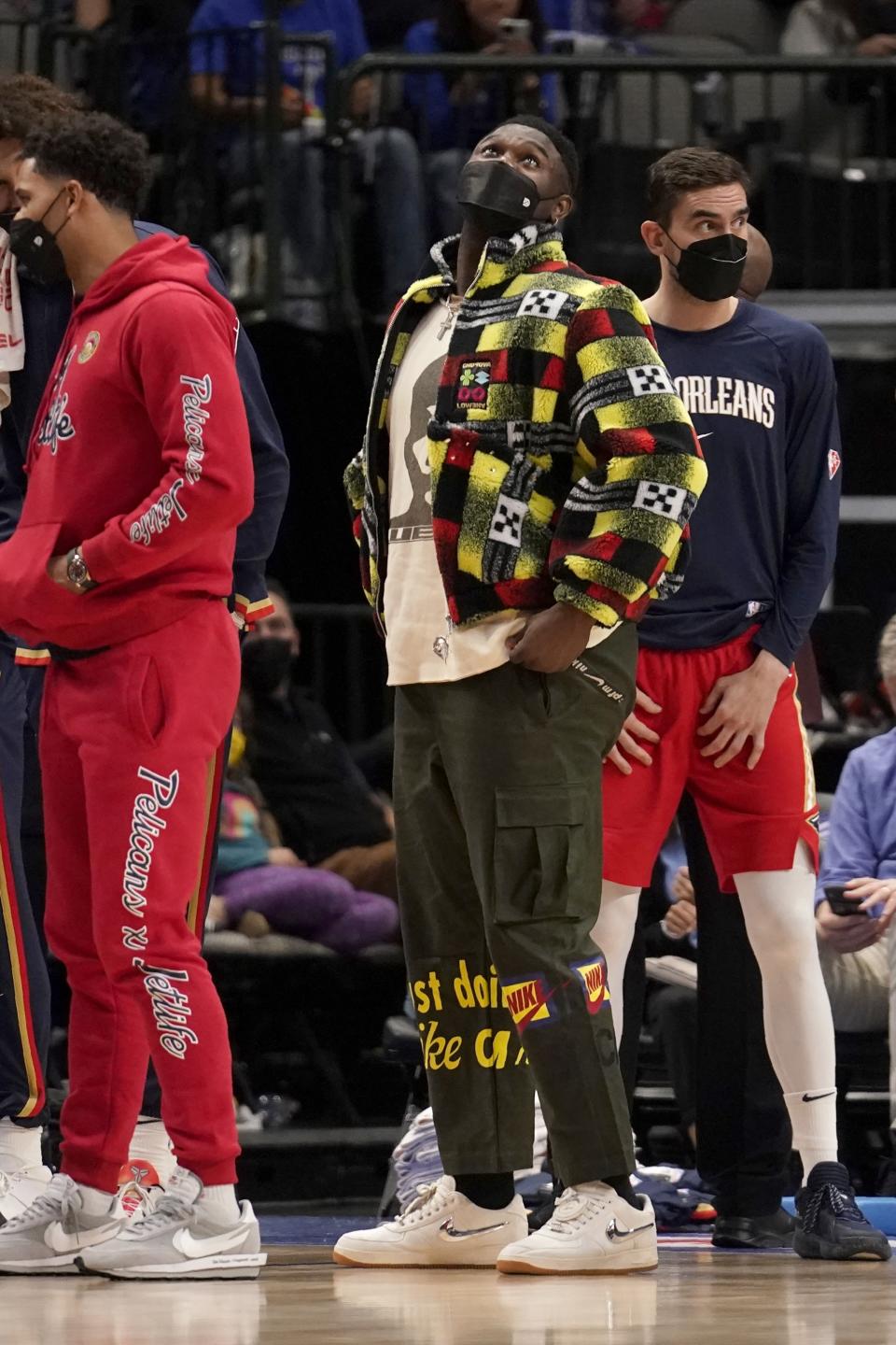 New Orleans Pelicans' Zion Williamson, center, watches the videoboard during a timeout in the second half of an NBA basketball game against the Dallas Mavericks in Dallas, Friday, Dec. 3, 2021. (AP Photo/Tony Gutierrez)