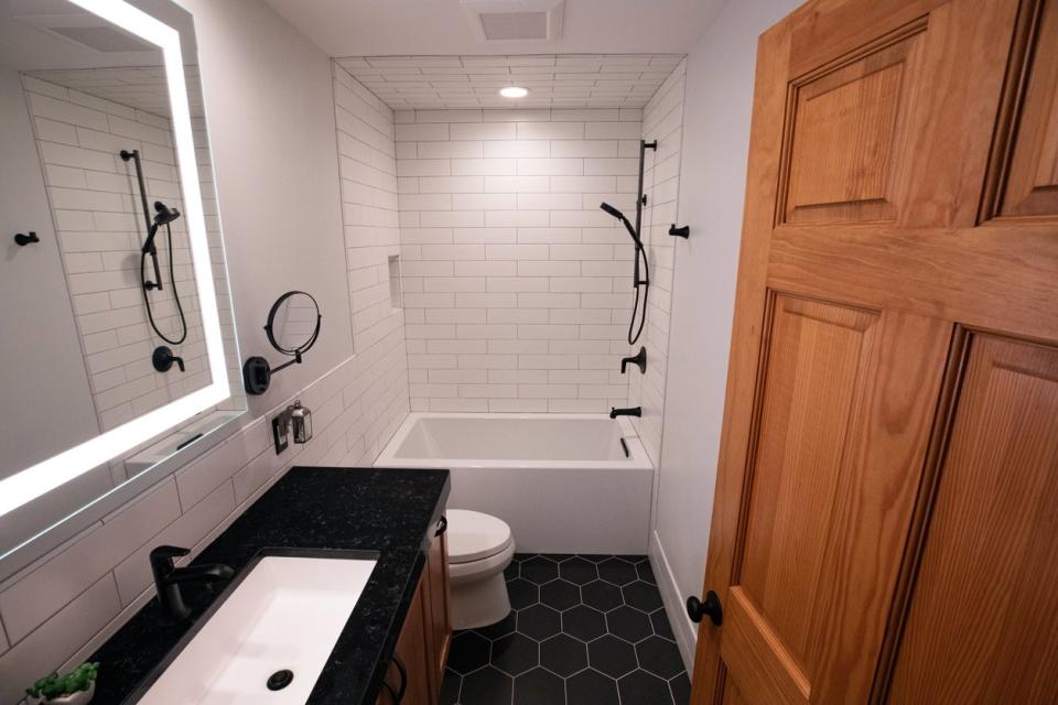 An open wood door leading into a small bathroom with a narrow bathtub on the far wall.