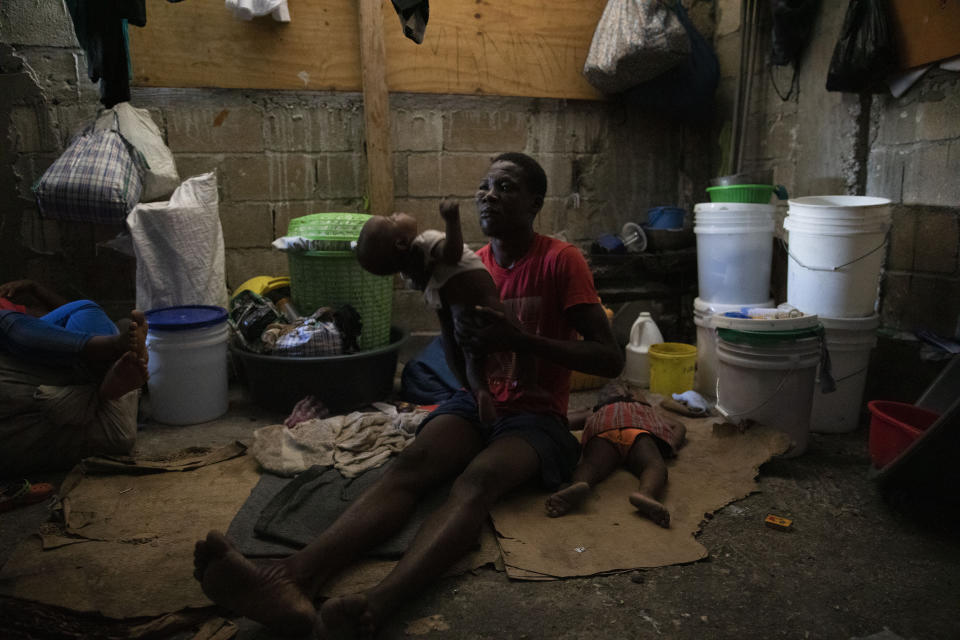 A man holds his baby boy at a shelter for families displaced by gang violence in Port-au-Prince, Haiti, Thursday, Dec. 9, 2021. More than 20,000 people have fled their homes due to gang violence this year, according to UNICEF, with many living in temporary shelters amid extremely unsanitary conditions and the pandemic. (AP Photo/Odelyn Joseph)