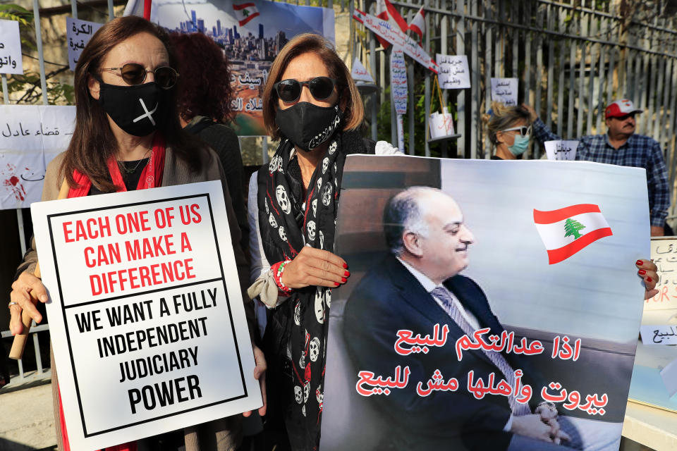 A Lebanese activists holds a placard showing a portrait of Lebanese judge Fadi Sawan who is in charge of the investigation of the August explosion in Beirut, with Arabic that reads: "if your justice is for sale, Beirut and its people not for sale," during a protest outside the justice palace, in Beirut, Lebanon, Thursday, Dec. 3, 2020. The blast was one of the largest non-nuclear explosions in history and six months later, political and confessional rivalries have undermined the probe into the Beirut port explosion and brought it to a virtual halt, mirroring the same rivalries that have thwarted past attempts to investigate political crimes throughout Lebanon's history. (AP Photo/Hussein Malla)