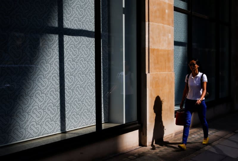 FILE PHOTO: The Burberry logo is pictured at a window as a woman walks past a Burberry office in central London