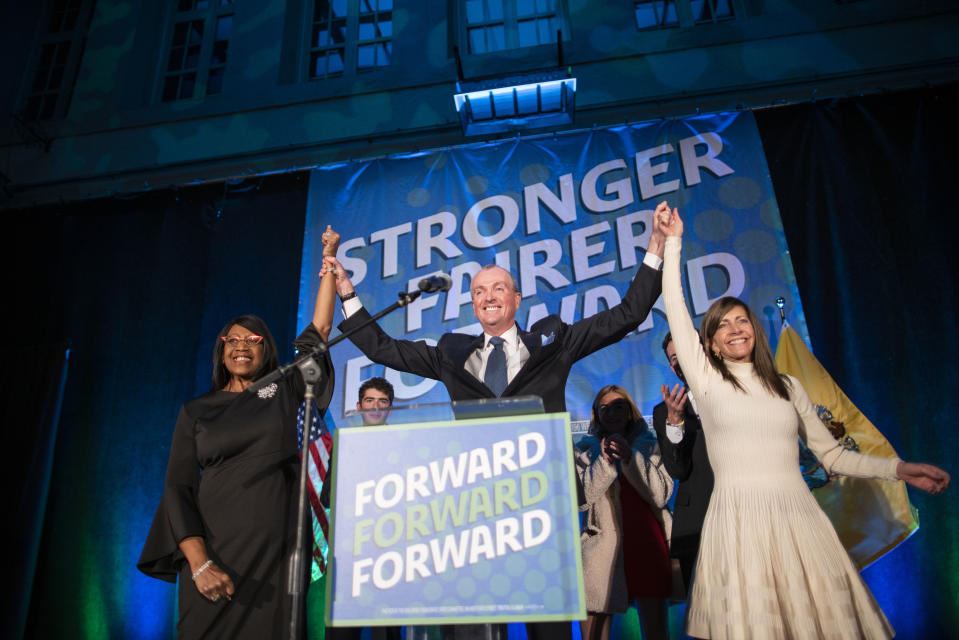New Jersey Gov. Phil Murphy, center, raises arms with first lady Tammy Snyder Murphy , right, and Lt. Gov. Sheila Oliver after speaking to supporters during an election party in Asbury Park, N.J., early Wednesday, Nov. 3, 2021. (AP Photo/Eduardo Munoz Alvarez)