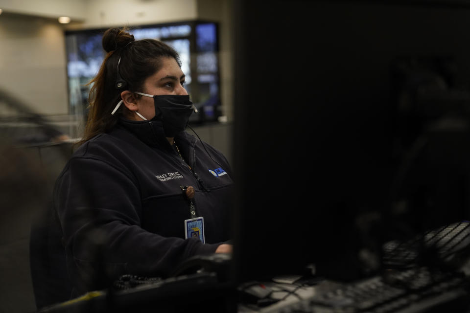 Dispatcher Ashley Cortez responds to a call in Care Ambulance Service's communication center in Santa Fe Springs, Calif., Saturday, Jan. 9, 2021. Dispatchers play chess with ambulances all day. When one gets stuck at a hospital for eight, 10 or 12 hours, the dispatchers must reposition the others to cover its area. When an EMT reports a positive COVID-19 test, the dispatchers must find a way to cover the ambulance's calls if the whole crew must quarantine. (AP Photo/Jae C. Hong)