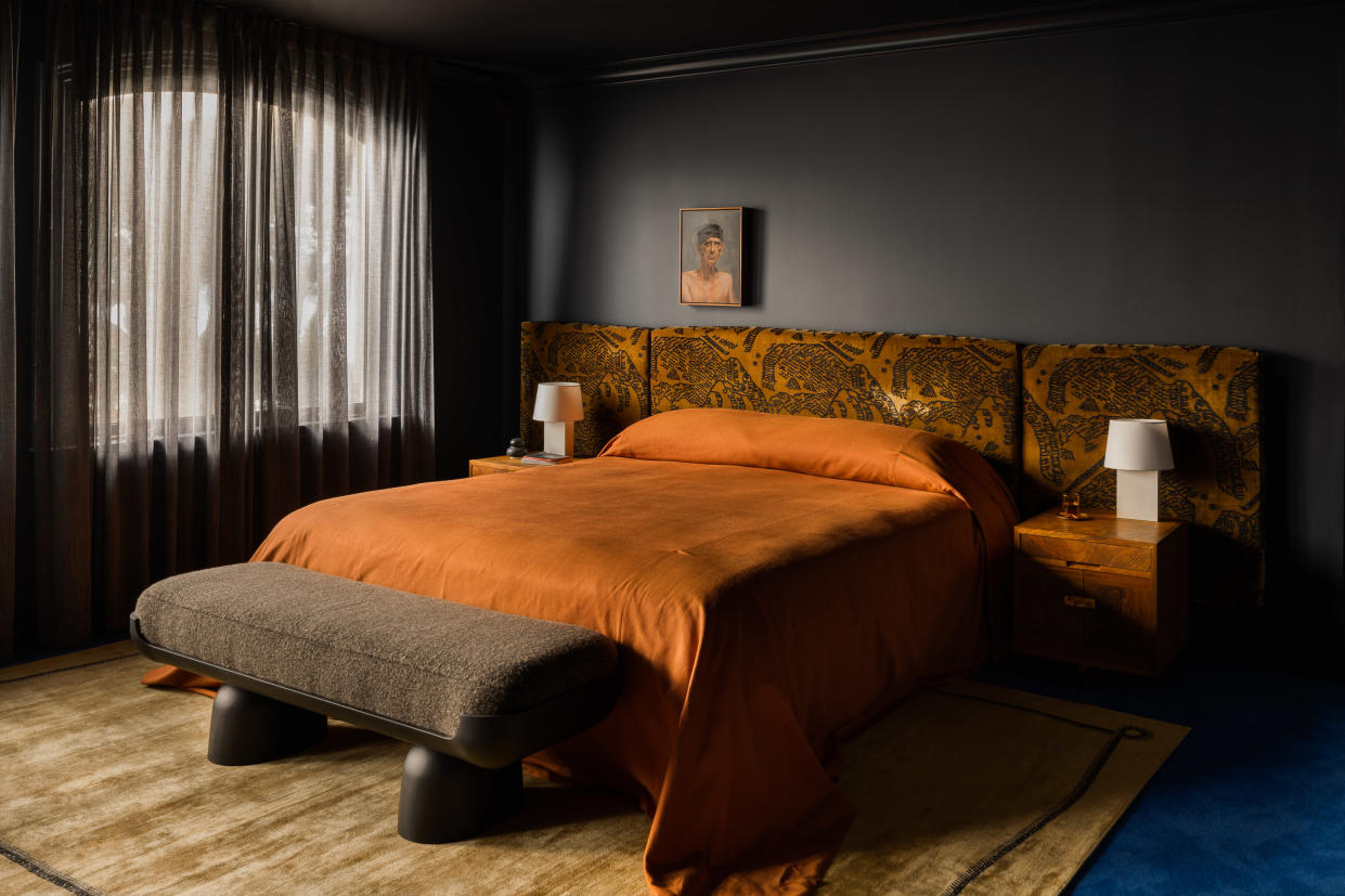  Dark bedroom with large bed and orange bedding. 