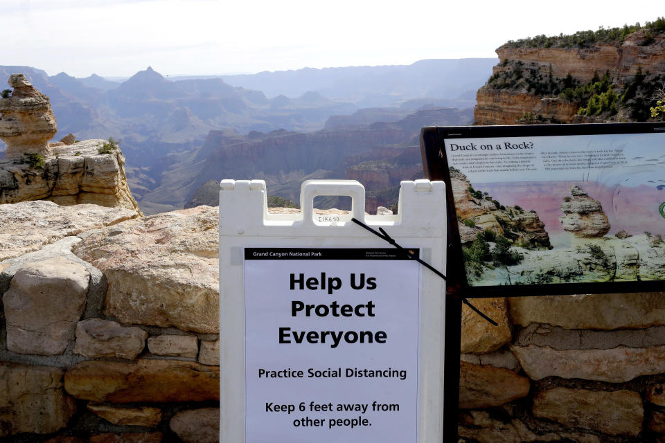 A social distancing sign is seen at the Grand Canyon Friday, May 15, 2020, in Grand Canyon, Ariz. Tourists are once again roaming portions of Grand Canyon National Park when it partially reopened Friday morning, despite objections that the action could exacerbate the coronavirus pandemic. (AP Photo/Matt York)