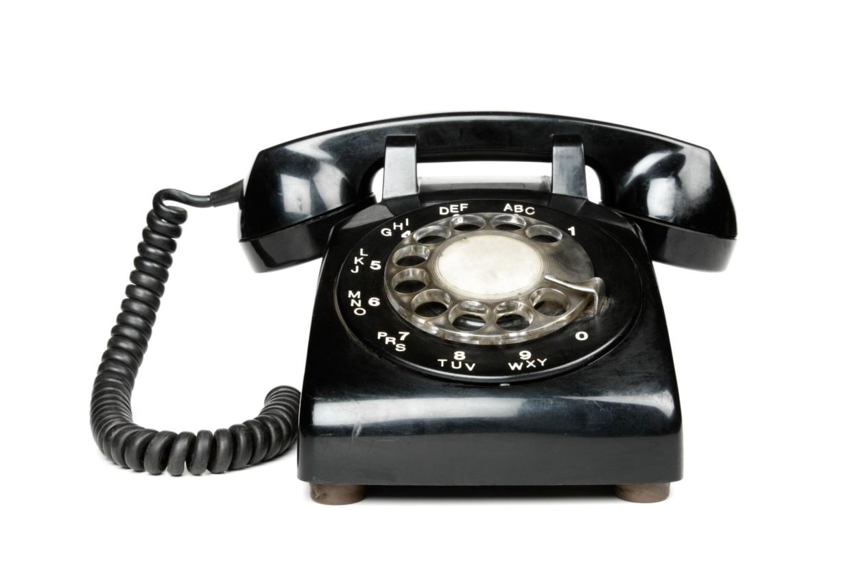 A black rotary telephone, isolated on a white background.