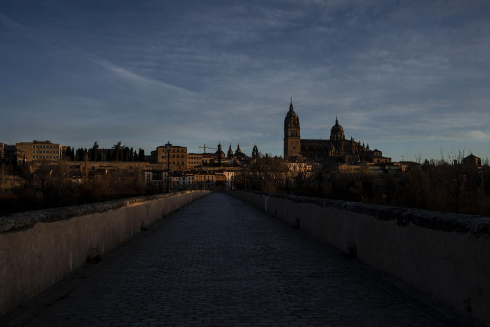 A Gothic cathedral, right, towers over Salamanca, Spain, seen from an ancient Roman bridge, on Sunday, Dec. 5, 2021. For the moment, the momentum -- in terms of church attendance and energy -- is toward the burgeoning ranks of Pentecostal and other evangelical congregations. (AP Photo/Manu Brabo)
