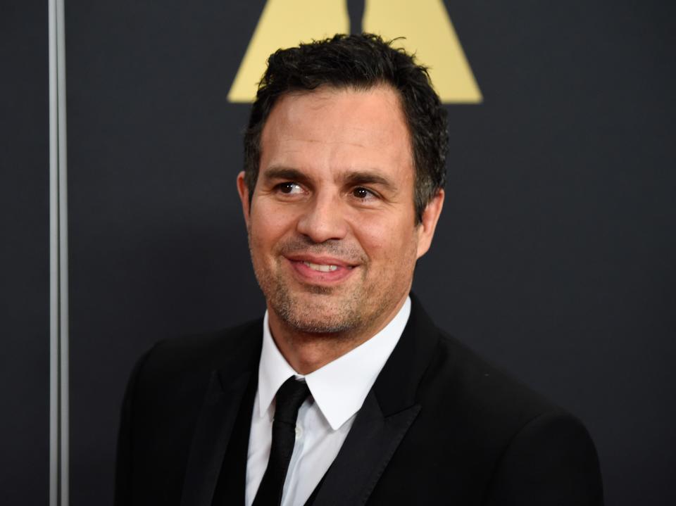 Mark Ruffalo at an event. He wears a black suit and tie.