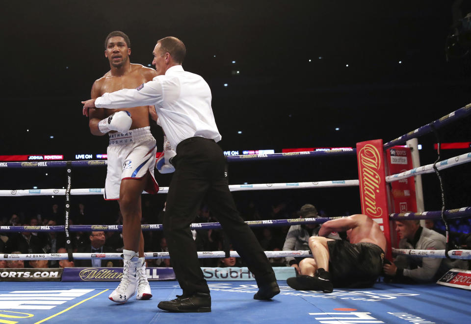 Britain's Anthony Joshua, left, is led away after knocking down Alexander Povetkin on his way to retaining his WBA, IBF, and WBO heavyweight boxing titles, Saturday, Sept. 22, 2018, at Wembley Stadium in London. (Nick Potts/PA via AP)