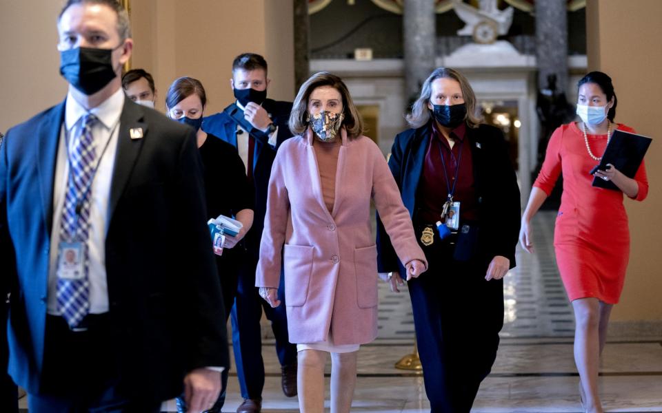 A masked Nancy Pelosi, flanked by staff, walks through Congres - Stefani Reynolds/Bloomberg