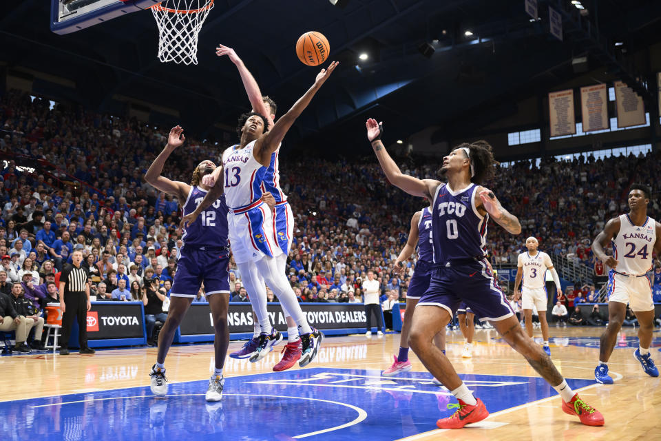 Kansas guard Elmarko Jackson (13) goes up for a rebound against TCU forward Xavier Cork (12) and TCU guard Micah Peavy (0) during the second half of an NCAA college basketball game in Lawrence, Kan., Saturday, Jan. 6, 2024. (AP Photo/Reed Hoffmann)