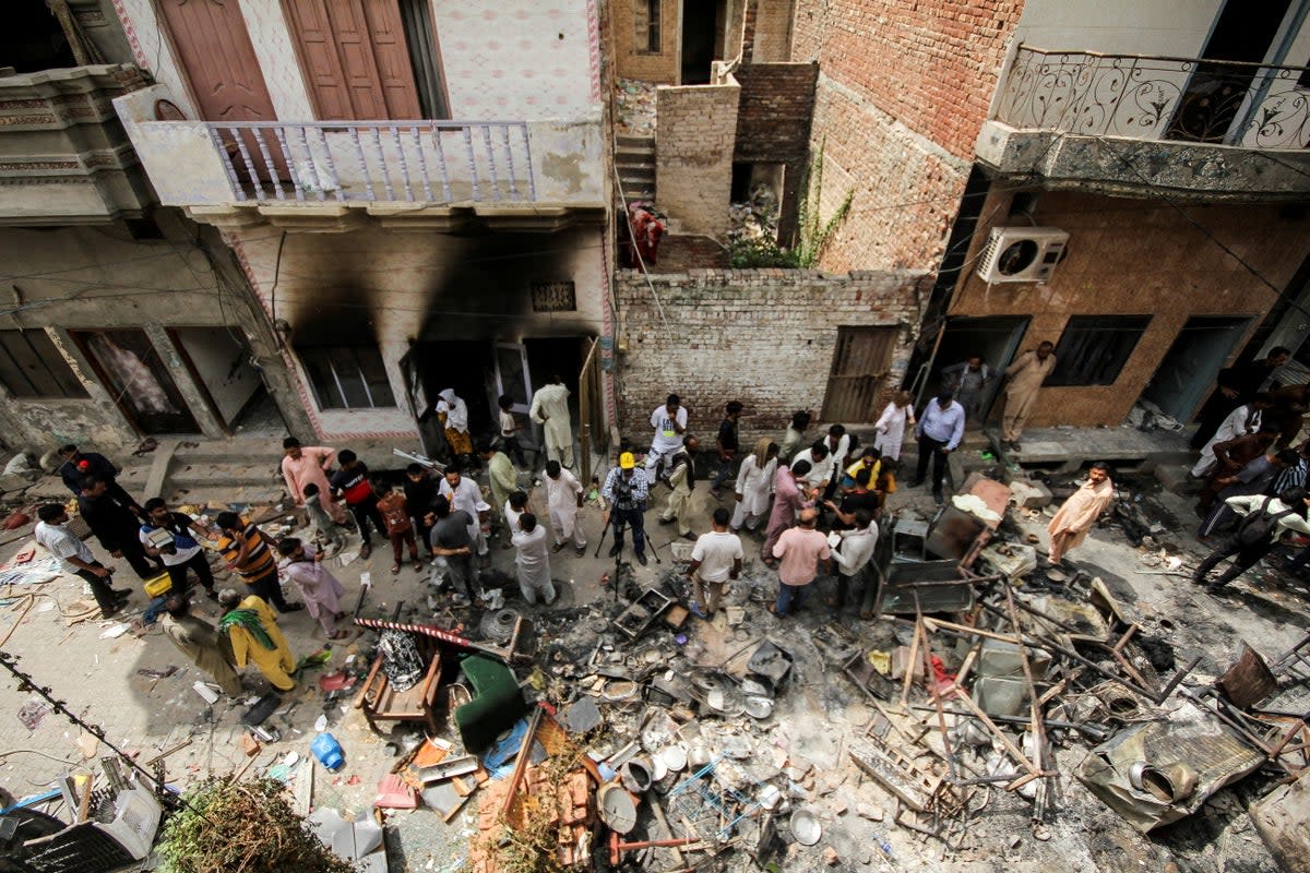 Onlookers and media representatives gather along a street in a Christian neighbourhood, a day after the church buildings and houses were vandalised by protesters in Jaranwala (Reuters)