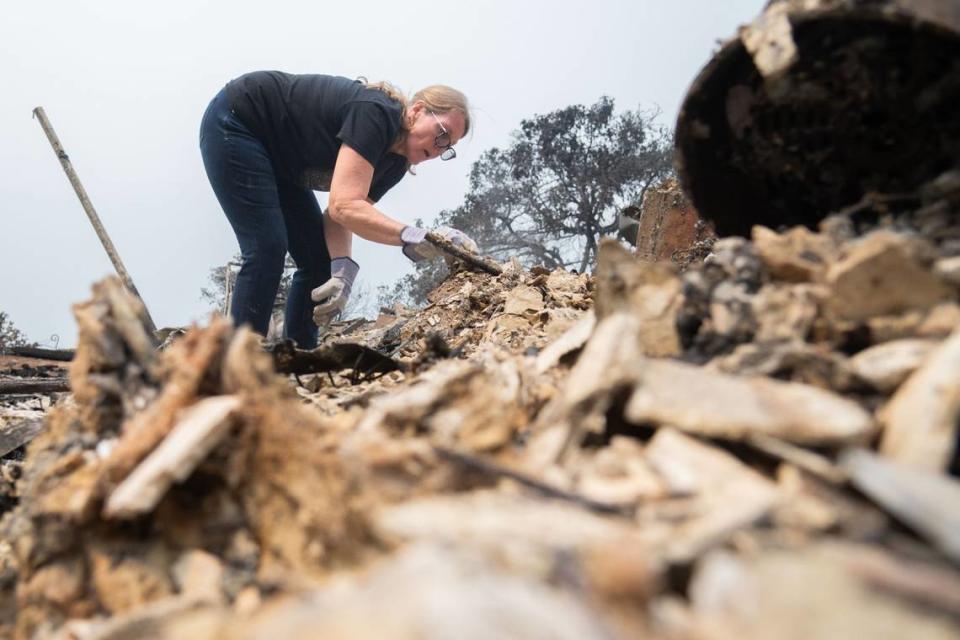 Linda Fischer picks through debris at her home in Forest Ranch on Wednesday. Although her neighbors’ homes were largely untouched by the Park Fire, hers was completely destroyed.