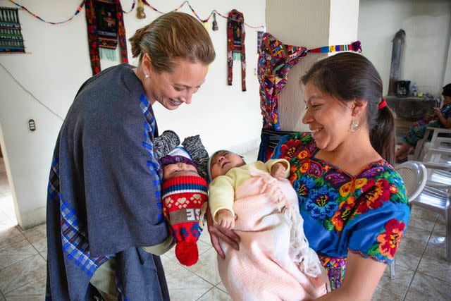 <p>Janet Jarman for Every Mother Counts</p> Christy Turlington Burns and a traditional midwife hold babies in Guatemala during an Every Mother Counts trip in 2019.