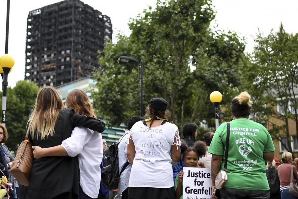 Support: Mourners hug in the shadow of the burnt-out tower block (Getty Images)