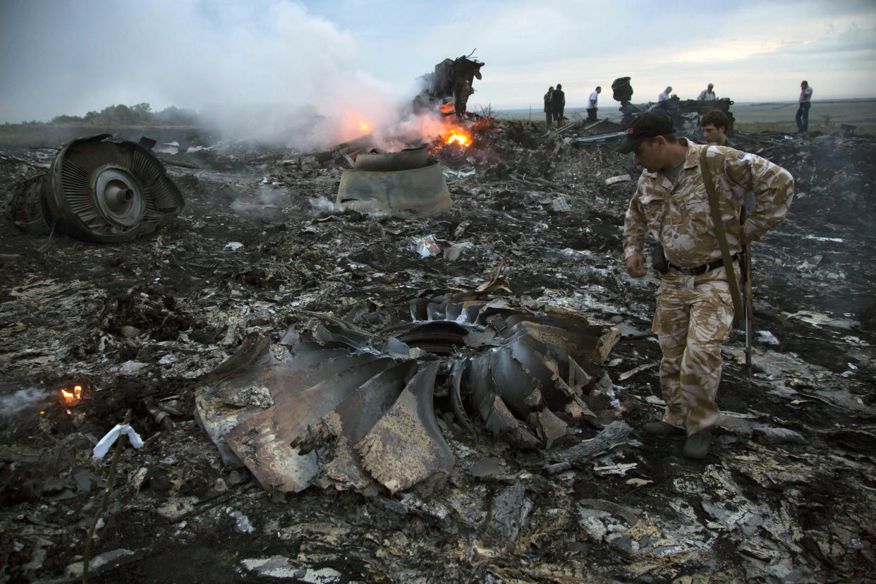 FILE - People walk amongst the debris at the crash site of a passenger plane near the village of Grabovo, Ukraine, July 17, 2014. An international team is presenting an update Wednesday Feb. 8, 2023 on its investigation into the 2014 downing of Malaysia Airlines flight MH17 over eastern Ukraine. The announcement comes nearly three months after a Dutch court convicted two Russians and a Ukrainian rebel for their roles in shooting down the Boeing 777 and killing all 298 people on board on July 17, 2014. (AP Photo/Dmitry Lovetsky, File)