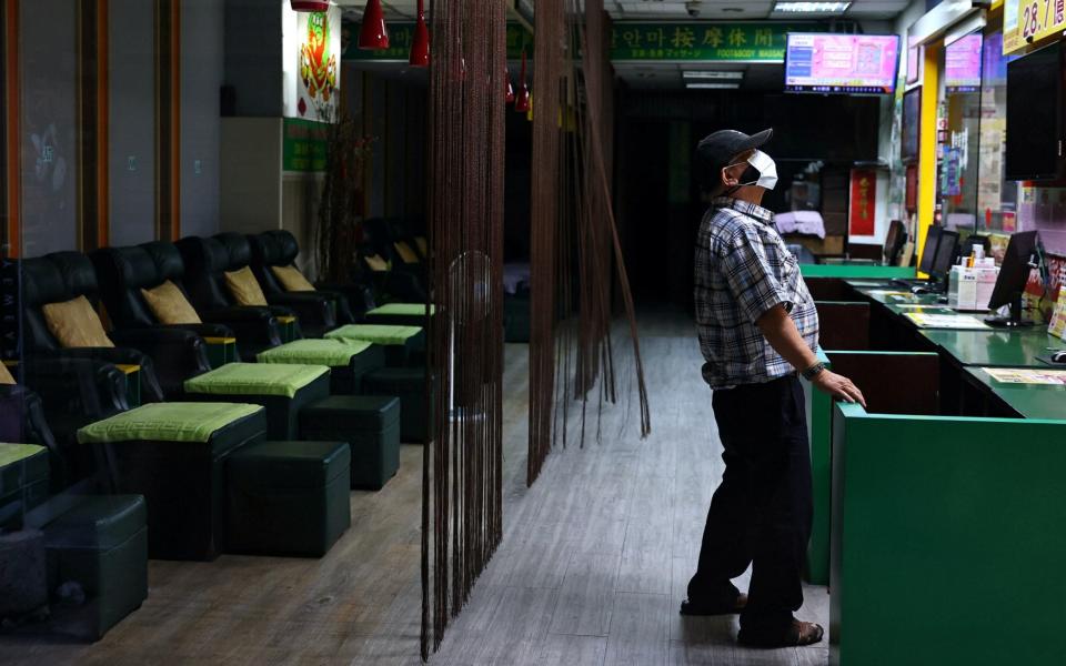 A man wearing a protective face mask stands at a closed massage shop after several venues were ordered to close amid an increasing number of COVID-19 infections, in Taipei, Taiwan - ANN WANG / REUTERS