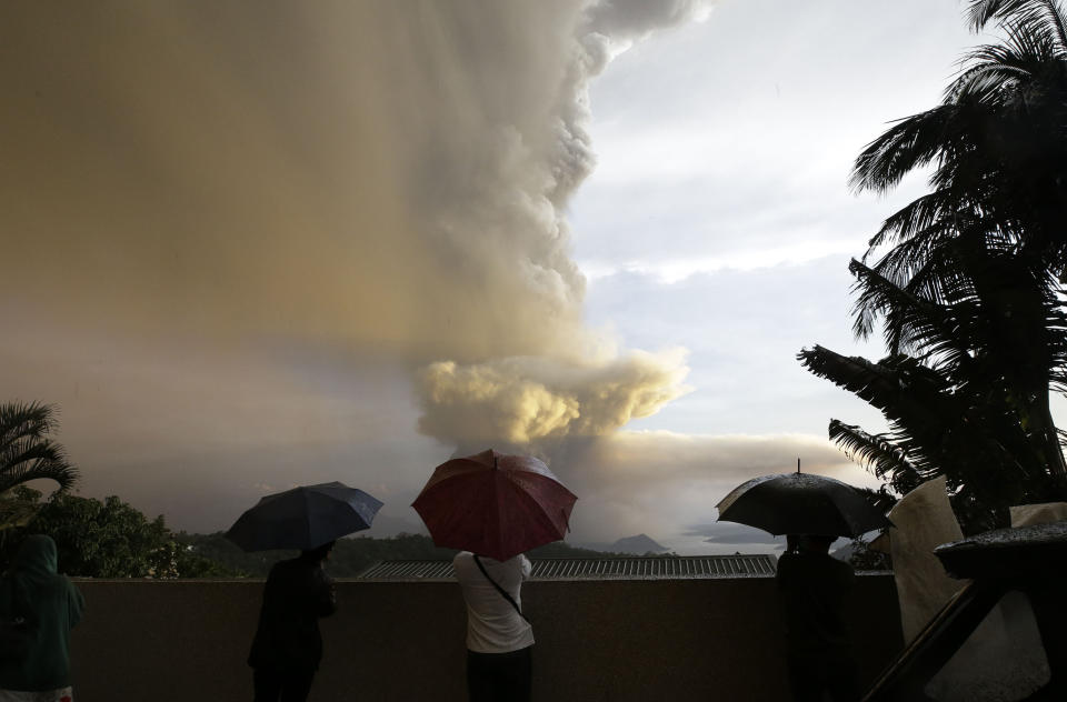 People watch as Taal Volcano erupts Sunday Jan. 12, 2020, in Tagaytay, Cavite province, outside Manila, Philippines. A tiny volcano near the Philippine capital that draws many tourists for its picturesque setting in a lake belched steam, ash and rocks in a huge plume Sunday, prompting thousands of residents to flee and officials to temporarily suspend flights. (AP Photo/Aaron Favila)