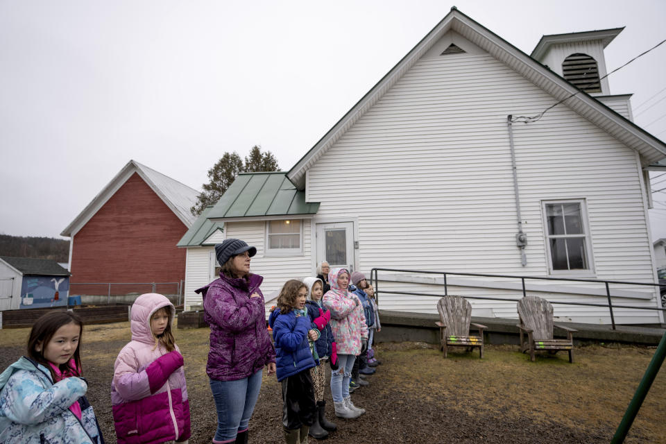 Classroom aid Ericka Bellavance, third from left, leads students in the Pledge of Allegiance outside the Elmore School, the last one-room schoolhouse in the state, Wednesday, March 6, 2024, in Elmore, Vt. In Elmore, population 886, its residents are used to holding tight to traditions. They've fought to keep open their post office, their store and their school. Last fall, Elmore residents voted 2-1 in favor of keeping their town meetings. (AP Photo/David Goldman)