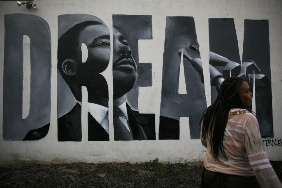 Lorinda Lacy, 45, stands outside her party store painted with a mural depicting Martin Luther King Jr. in the Watts neighborhood of Los Angeles, Tuesday, June 30, 2020. Lacy moved out of Watts 20 years ago because she didn't want her daughters to grow up with the trauma she experienced as a girl. She said she eventually became "immune" to the violence after stepping over bodies on the way to school and finding out who had been killed the night before or who had their house shot up. (AP Photo/Jae C. Hong)