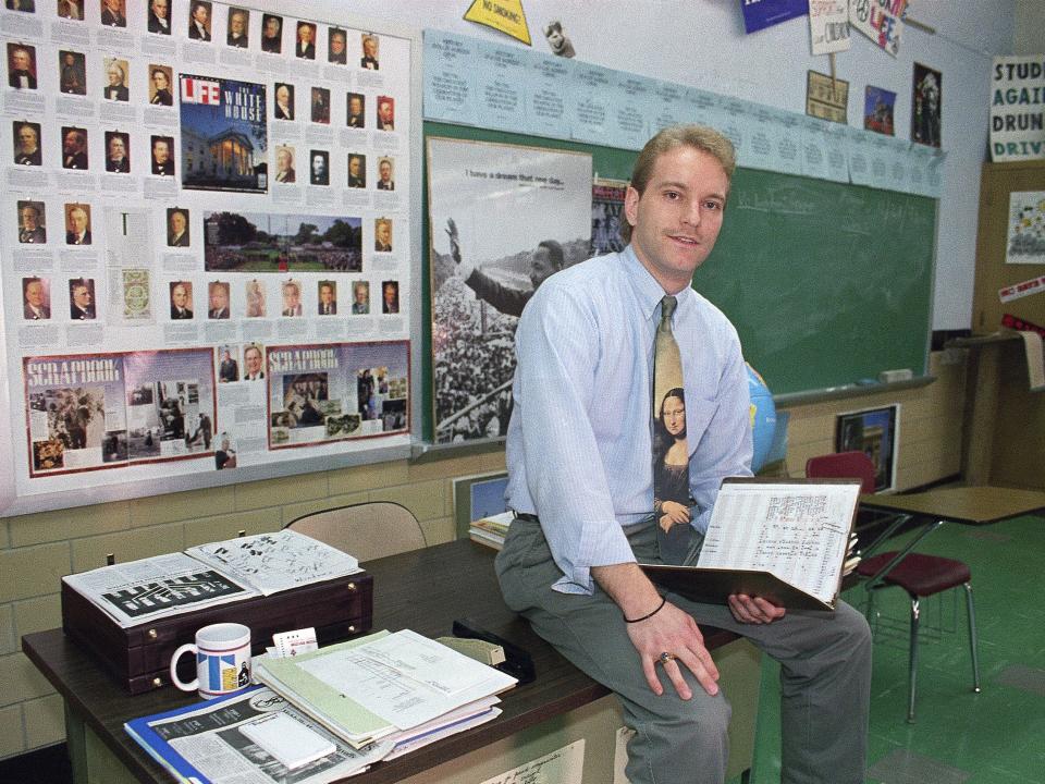 Melville High School teacher Rodney Wilson sits on his desk in a classroom in 1994