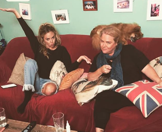 Angie Kent and Yvie Jones pose on their couch, where they starred on Gogglebox 