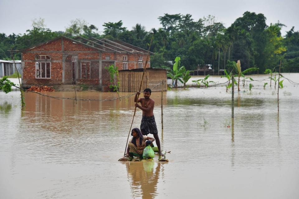 Villagers on a raft make their way past homes in a flooded area after heavy rains in Nagaon district, Assam state, on 21 May (AFP/Getty)