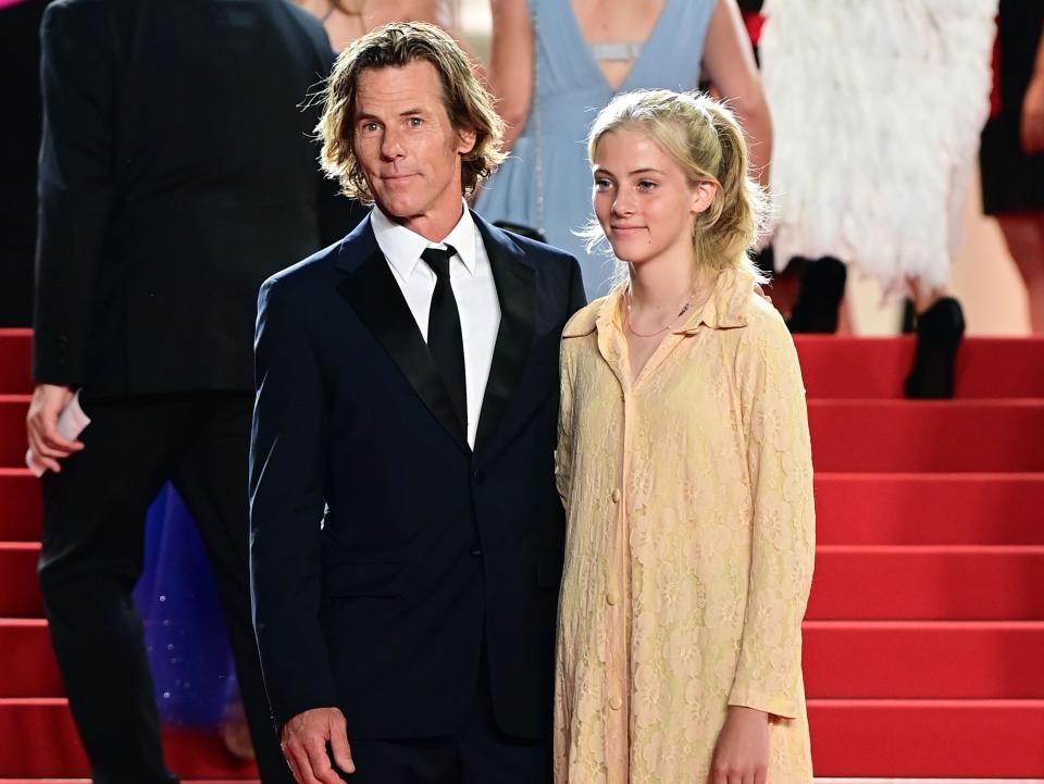 Cinematographer Daniel Moder wears a black suit and poses on the red carpet at Cannes with daughter Hazel, in a yellow dress and black shoes.