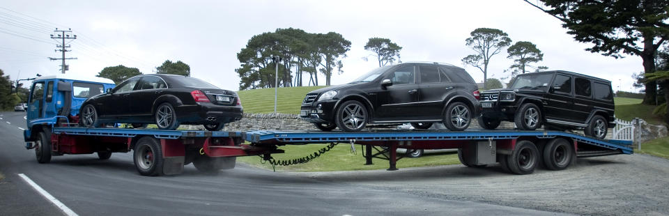 FILE - In this Jan. 20, 2012 file photo , a trailer truck takes away luxury cars which were seized from Kim Dotcom's house in Coatesville, north west of Auckland, New Zealand. On his way up, he fooled them all: journalists, judges, investors and companies. Then the man who renamed himself Kim Dotcom finally did it. With an eye for get-rich schemes and an ego gone wild, he parlayed his modest computing skills into a mega-empire, becoming the fabulously wealthy computer maverick he had long claimed to be. (AP Photo/NZ Herald, Natalie Slade, File) NEW ZEALAND OUT, AUSTRALIA OUT