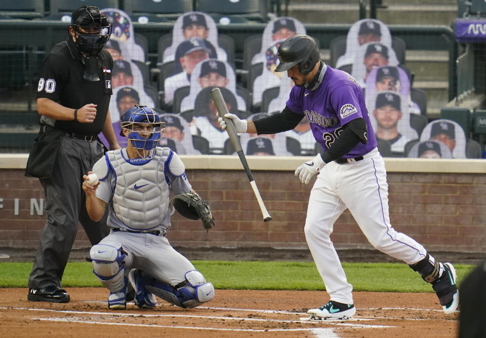 Colorado Rockies' Nolan Arenado reacts after striking out against Los Angeles Dodgers starting pitcher Alex Wood, while catcher Austin Barnes, center, and home plate umpire Mark Ripperger watch during the first inning of a baseball game Friday, Sept. 18, 2020, in Denver. (AP Photo/David Zalubowski)