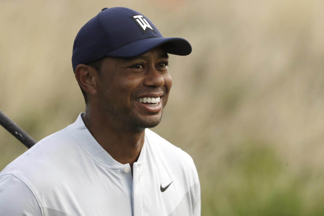 Tiger Woods smiles after teeing off on the 12th hole in the Northern Trust tournament at Liberty National Golf Course, Thursday, Aug. 8, 2019, in Jersey City, N.J. (AP Photo/Mark Lennihan)