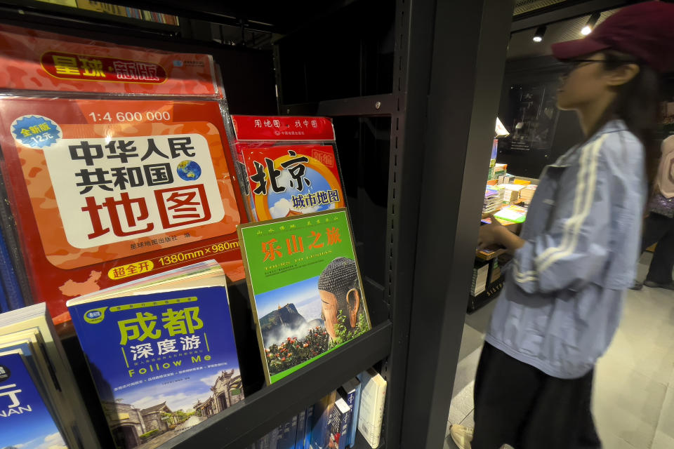 A woman walks by the new China's map which printed on January this year on display for sale at a bookstore in Beijing, Friday, Sept. 1, 2023. China has upset many in the Asia-Pacific region with the release of a new official map that lays claim to most of the South China Sea, as well as contested parts of India and Russia, and official objections continue to mount. (AP Photo/Andy Wong)
