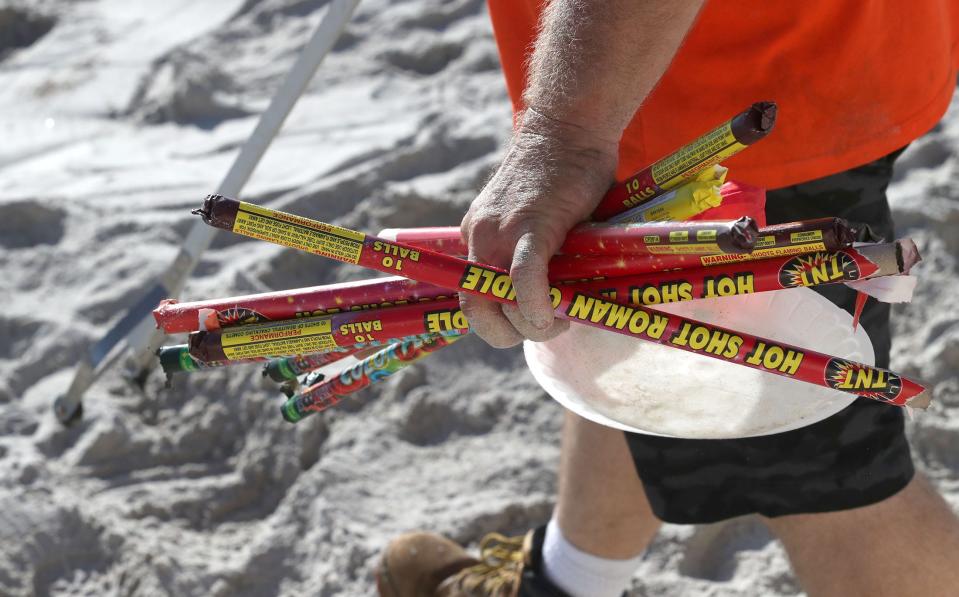 A CFB Outdoors employee picks up discarded Roman candle tubes left behind on Volusia beaches after July 4th celebrations in 2022.