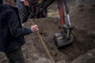 CAPTION CORRECTS LOCATION -Volunteers remove the soil from a mass grave during an exhumation of four civilians killed in Mykulychi, Ukraine on Sunday, April 17, 2022. All four bodies in the village grave were killed on the same street, on the same day. Their temporary caskets were together in a grave. On Sunday, two weeks after the soldiers disappeared, volunteers dug them up one by one to be taken to a morgue for investigation. (AP Photo/Emilio Morenatti)