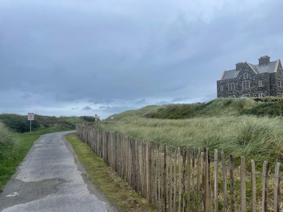 Path leading to Trump International Hotel with grass and wooden fence in foreground