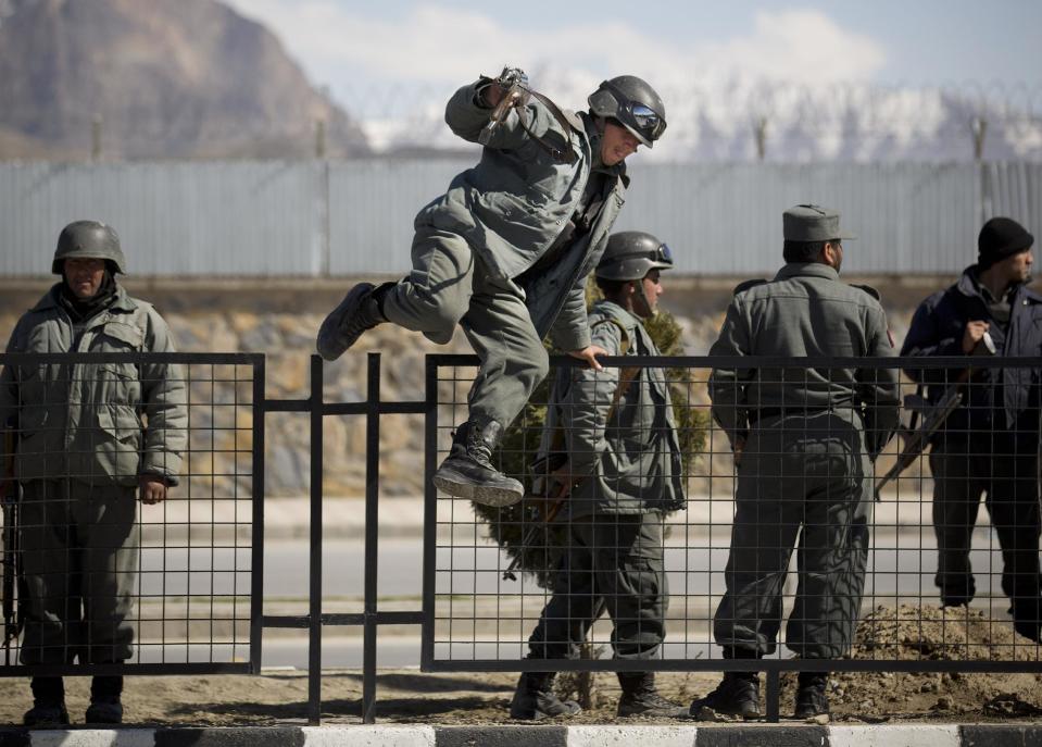 Afghan policemen arrive to the scene after the Taliban launched an assault with a suicide bomber detonating his vehicle outside an election office in Kabul, Afghanistan, Tuesday, March 25, 2014. Gunmen stormed into the building, trapping dozens of employees inside and killing many people. A candidate for a seat on a provincial council was among those killed, along with an election worker, a civilian and a policeman. (AP Photo/Anja Niedringhaus)