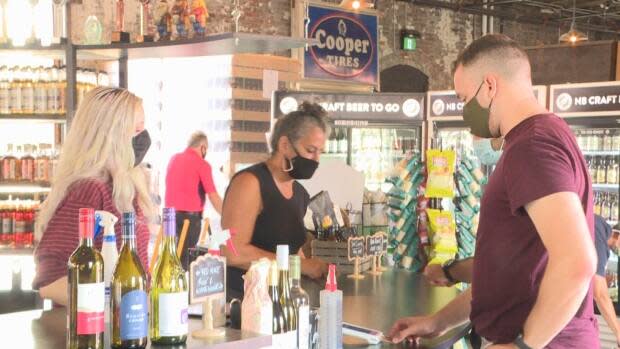 The Picaroons Roundhouse general manager Lisa Wilby (middle) says most customers at the Fredericton business have been happy to comply with the proof of vaccination requirement. (Mrinali Anchan/CBC - image credit)